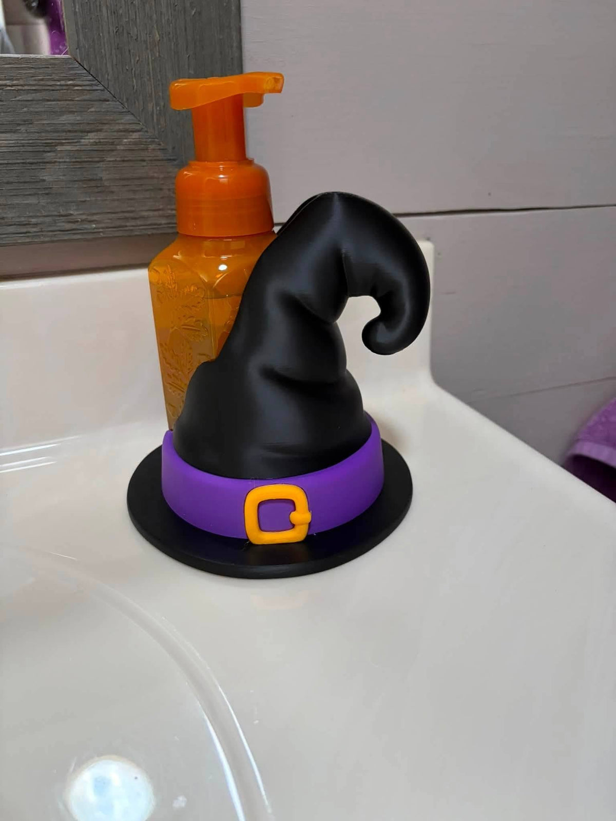 A Halloween-themed black witch hat soap holder holding bath and body works hand soap
